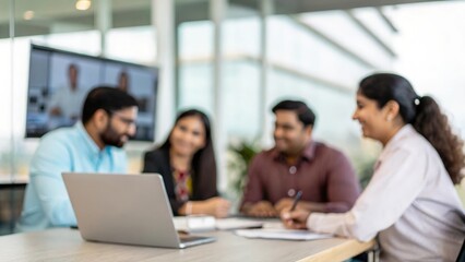 Blurred view of Indian business team attending virtual meeting in modern office
