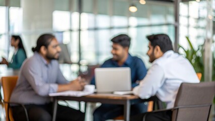 Blurred corporate workspace with Indian colleagues gathered for strategy discussion
