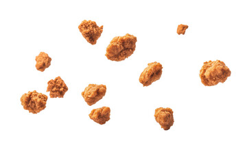 Falling nuggets create a delightful sprinkle effect against a white background, showcasing their texture and shape during a playful descent