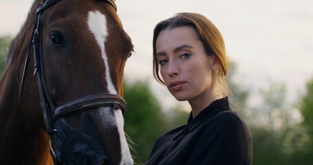 Portrait of a woman with a horse on a summer day. A woman lovingly strokes a horse's muzzle