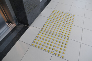 Yellow tactile ground indicators near elevator entrance