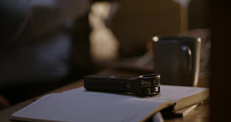 A voice recorder on the detective's desktop. A man picks up a dictaphone, close-up of his hand, an...