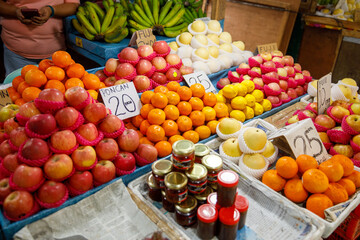 Apples, poncan oranges, lemons, and bottled jam at fruit stall in Philippines market with handwritten signs