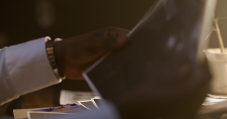 The detective examines the photographs. Close-up of his hands, unrecognizable persona