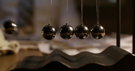 Newton's pendulum on the desk in the office. The balls are moving. Close-up