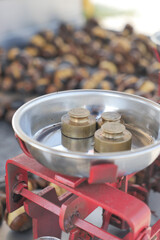 Weighing roasted chestnuts on a traditional scale