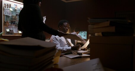 Working in a police office. A woman brings folders with documents to her colleagues
