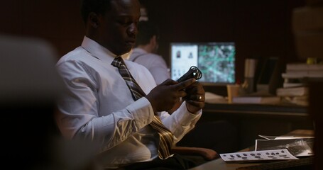 A detective listens to an audio recording on a dictaphone. He works in the office next to his...