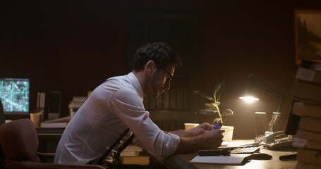 The detective is concentrating while sitting at his desk in the office