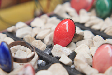 Colorful rings displayed on small stones at a market