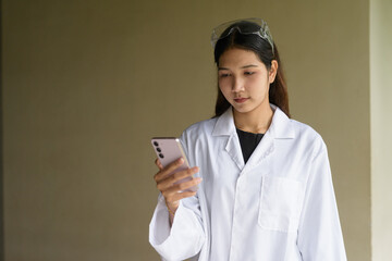 Scientist woman wearing lab coat and goggles using mobile phone