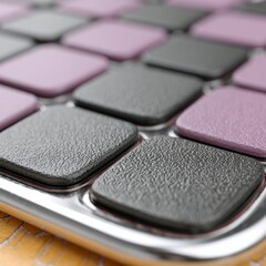 Close up view of textured square pads in alternating grey and purple colors on a metallic surface