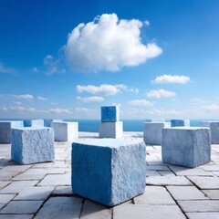 Serene blue and white stone cubes arranged on a paved surface against a vibrant sky and ocean backdrop