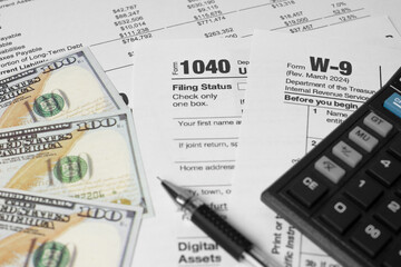 Obraz premium Financial planning concept with U.S. tax form 1040, pen, calculator, and spread of dollar bills. Symbolizing income tax return, budgeting, accounting, and personal finance management.