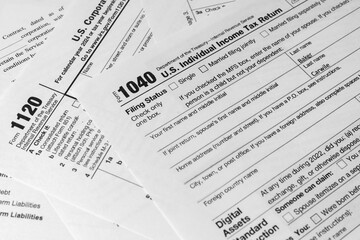 Obraz premium Stack of U.S. tax forms including IRS 1040. Concept of income tax filing, federal documentation, and personal finance management.