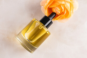 Cosmetic dropper bottle with a natural face and body care product on a light background with a rose . top view. A copy space. A blank bottle mockup.