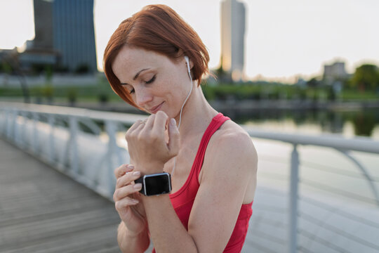 Runner checking her performance on a smartwatch during her morning run across a city bridge.
