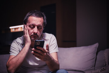 Tired exhausted man reading text message on mobile phone
