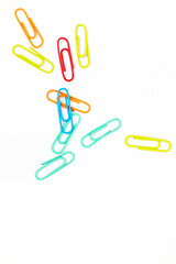 Colorful paper clips scattered on a white background, ideal for office or school supplies