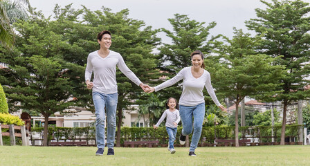 Portrait of happy family mother father daughter exercise runin the park spring summer time. Asian parent man woman and little girl smile playing . Health care together love lifestyle