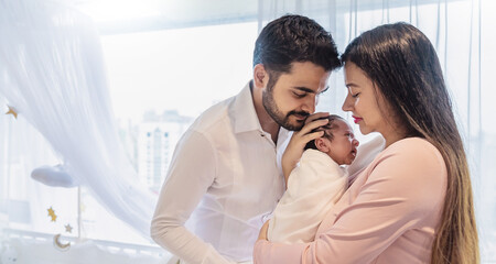 Portrait of Asian parents newborn baby day, Closeup of asian young couple father mother holding new born baby in hospital bed. Happy asia lovely family, nursery home breastfeeding mother’s day