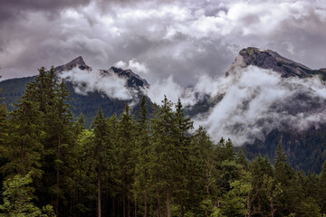 tief hängende Wolken in den Bergen. im Vordergrund Nadelwald am Hintersee in den Alpen bei Berchtesgarden in Deutschland