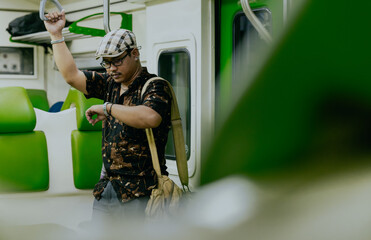 Tourist asian man with backpack traveling by public transportation or MRT train while checking...