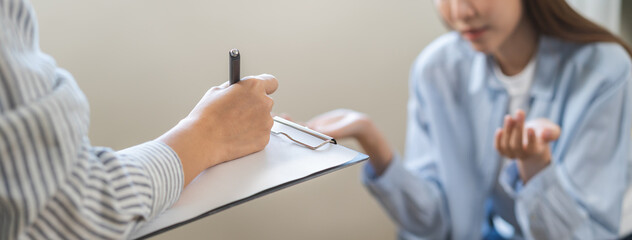 Psychology, depression. Suffer asian young woman consultation with psychologist while patient counseling mental therapy, doctor hand taking notes at clinic. Psychologist with sick mental health person