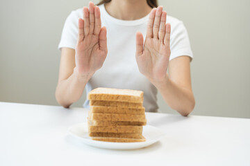 Gluten allergy, asian young woman hand push out, refusing to eat white bread slice on plate in...