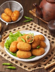 Kroket kentang. Croquettes are lumps of finely mashed potatoes filled with seasoned minced meat and mixed with vegetables such as carrots or green beans. The croquettes are coated with beaten egg and 
