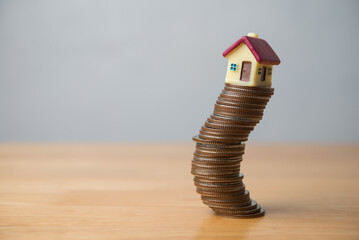 House on stack coins in uncertainty situation on wooden table. Risk and financial management in...