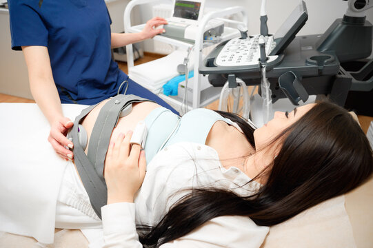 Pregnant woman undergoing cardiotocography procedure. CTG procedure to monitor fetal heartbeat and uterine contractions during pregnancy. A pregnant woman undergoes a medical examination.