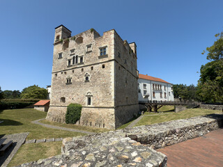 S&aacute;rospatak Castle, historic medieval fortress with stone tower and wooden bridge, located in Hungary, surrounded by green landscape under clear blue sky.
