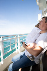 A man and a boy on a white boat in the sea are sitting by the side, father and son are enjoying a sea trip