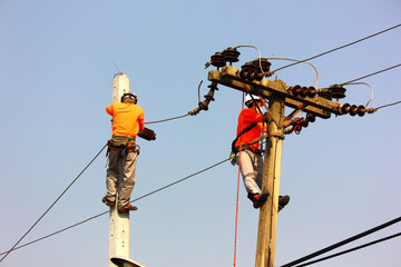 the electric worker are installing high voltage line on pole. workers put on safety belt helmet...