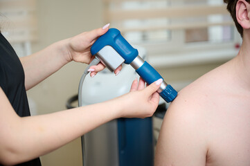Physical therapy of shoulder with acoustic shock waves. Close up view of doctor performing shock...