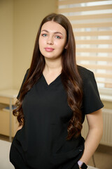 Portrait of young pretty female doctor in clinic wearing modern medical suit.