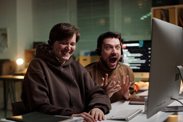 Caucasian woman and man wearing headsets using computer, woman smiling while man reacting with...
