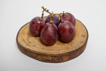 Juicy red grapes are placed on rustic wooden pieces.