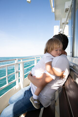 A man and a boy on a white boat in the sea are sitting by the side, father and son are enjoying a sea trip