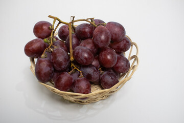 A healthy bunch of grapes sitting in a straw basket, perfect for a snack or fruit display.