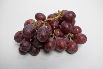 A fresh bunch of red grapes on a clean white surface, ready to enjoy.