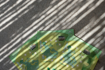 Euro banknotes. 100 euro banknotes on gray concrete with shadows. Shadow money. Business, finance,...
