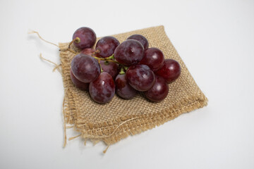 Red grapes on a folded burlap pad, combining freshness with rustic charm.