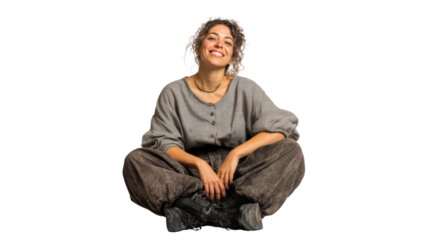 Joyful woman sitting on floor, smiling warmly, casual outfit, isolated on white background.