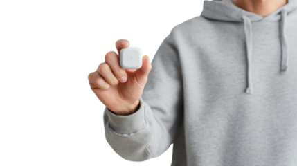Person wearing gray hoodie holding wireless earbuds on white isolated background.