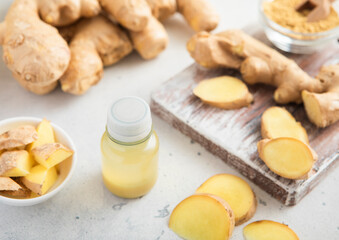 Immune ginger energy shot drink bottles with fresh raw ginger root on light background.Macro.
