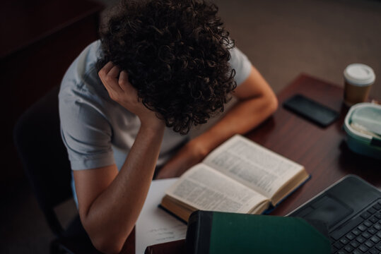 Tired student holding head while studying at desk