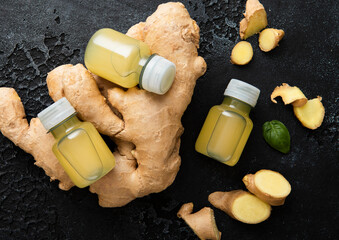 Bottles of immune ginger energy shot drink with ginger roots on black background.Macro.