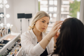 Professional makeup artist applying makeup on model in beauty salon